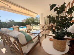 A sunlit outdoor seating area with a pool, wicker furniture, and potted plants. - Holiday Home 'Tres' with Private Pool, Private Terrace and Wi-Fi (Es mercadal)