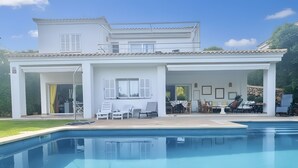 A two-story house with a swimming pool, outdoor seating, and a covered patio area.