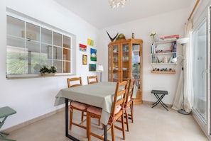 A dining area with a table, chairs, a cabinet, and a window. - Holiday Home 'Tres' with Private Pool, Private Terrace and Wi-Fi (Es mercadal)