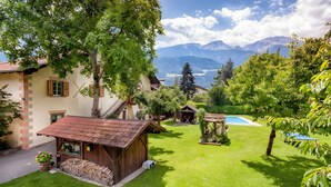 Un jardín bien cuidado con un cobertizo de madera, un perro descansando y una vista a la montaña al fondo.