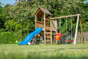 Une structure de jeu en bois avec un toboggan et des balançoires.
