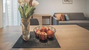 Ein Esstisch mit einer Vase weißer Tulpen und einem Drahtkorb mit Äpfeln.