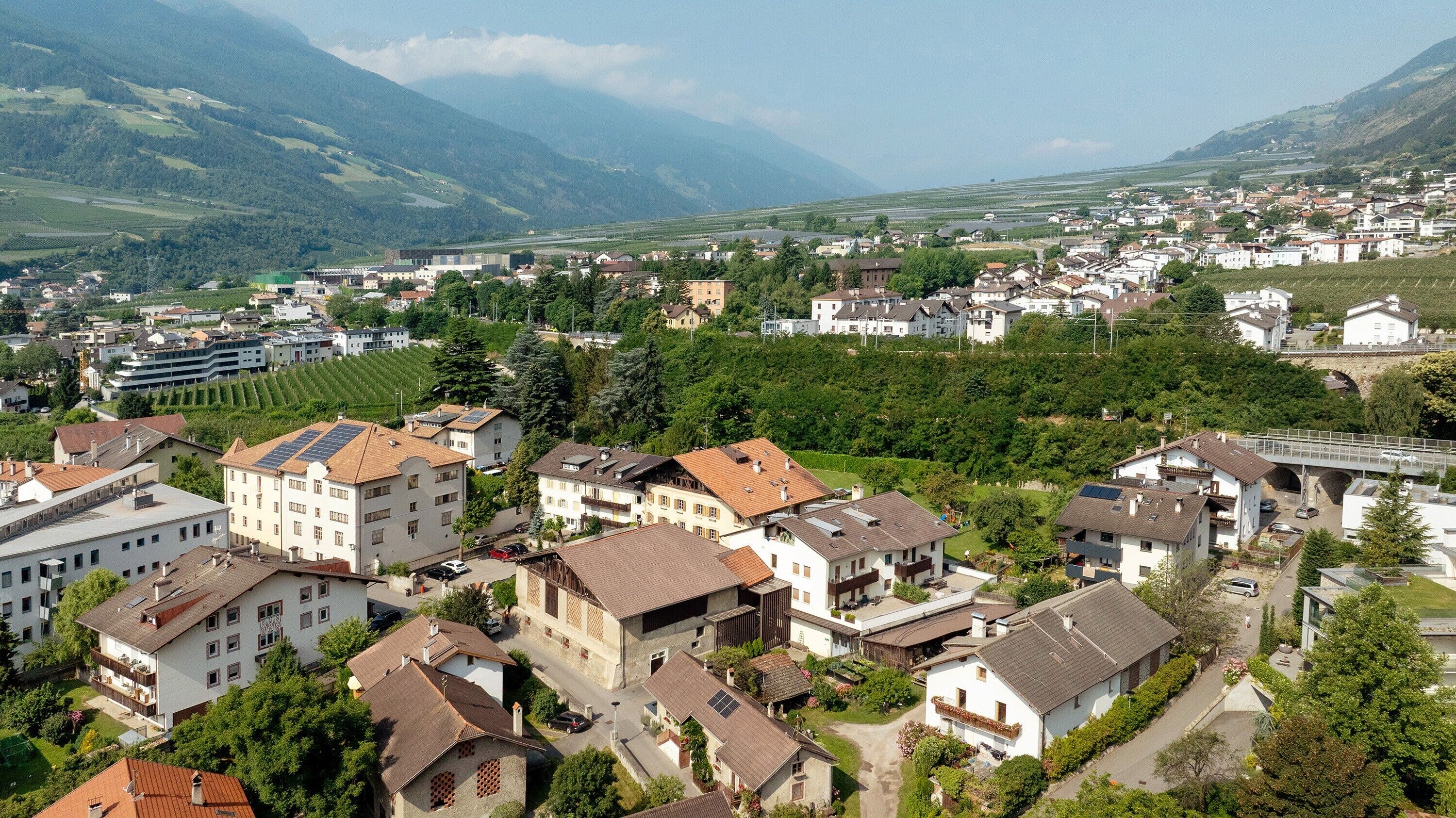 Un quartiere residenziale con case, un ponte e montagne sullo sfondo.