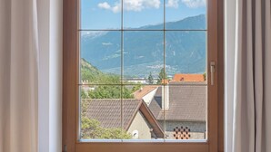 A window with a view of a mountainous landscape and residential buildings.