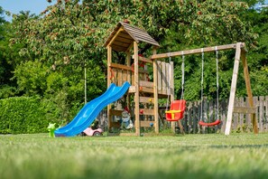 A wooden play structure with a slide and swings.