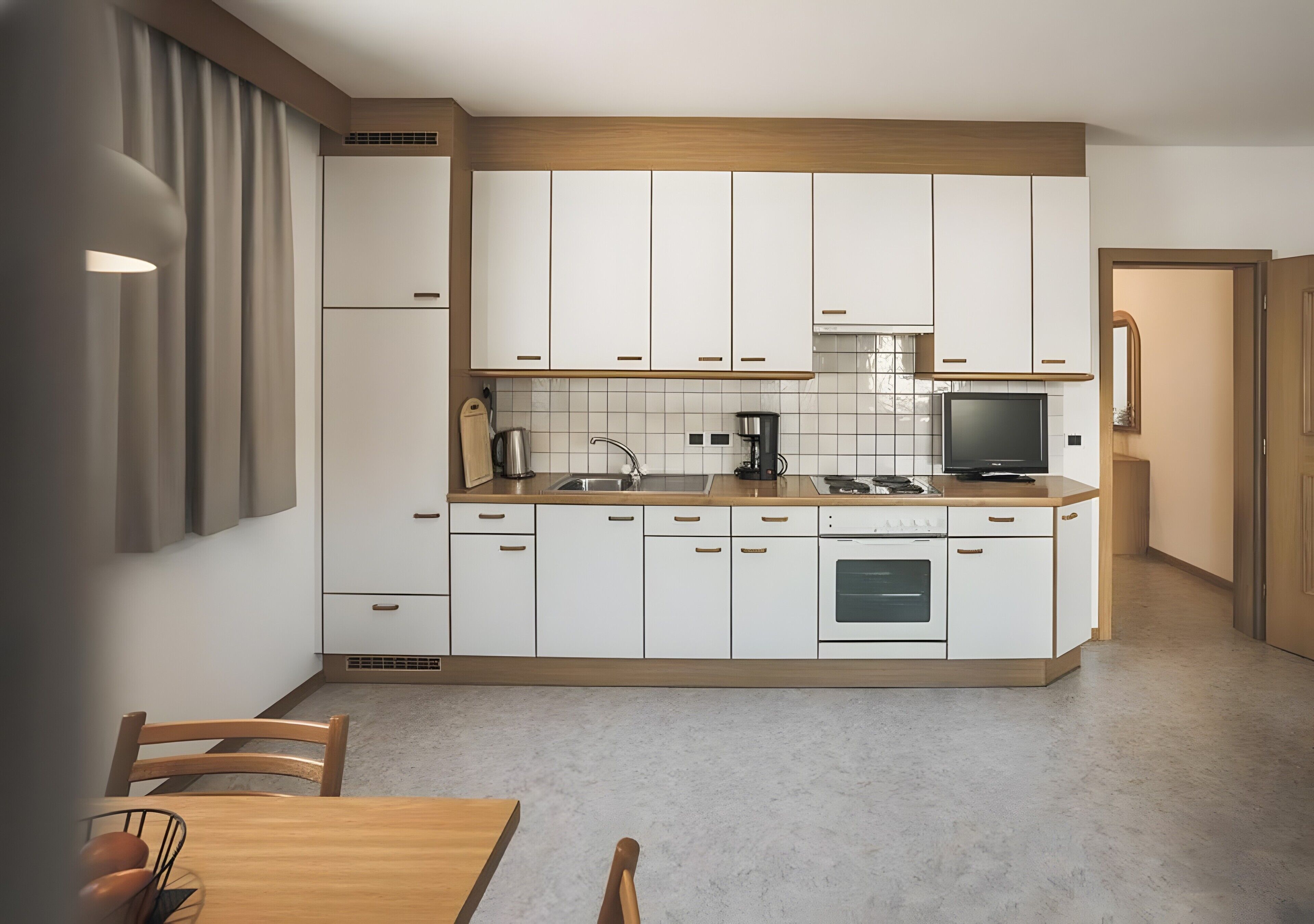A modern kitchen with white cabinets, a wooden countertop, a built-in oven, and a dining area with a wooden table and chairs.