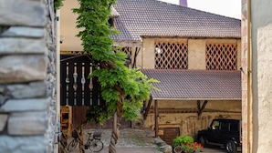 Un bâtiment rustique avec un toit en tuiles, un vélo et un véhicule garé.