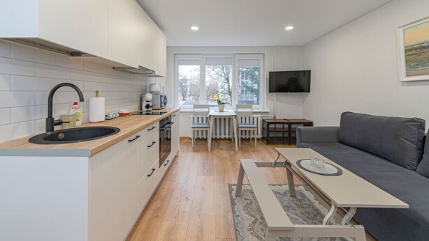 Una cocina moderna con un lavamanos, estufa y comedor con una mesa y sillas.