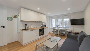 Un espacio habitable compacto con kitchenette, comedor y sofá.