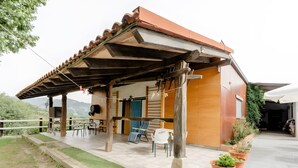A covered outdoor seating area with chairs and tables, a wooden pergola, and potted plants. - Chalet 'Alarpe Aterpetxea' with Mountain Views, Shared Terrace and Garden (Zaldibia)