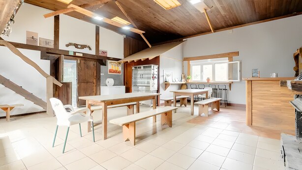 A spacious room with wooden beams, a kitchen area, and a dining space with benches and chairs. - Chalet 'Alarpe Aterpetxea' with Mountain Views, Shared Terrace and Garden (Zaldibia)