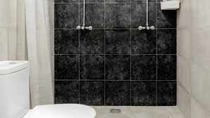 A bathroom with a white toilet, a shower with black marble tiles, and a green rug. - Chalet 'Alarpe Aterpetxea' with Mountain Views, Shared Terrace and Garden (Zaldibia)