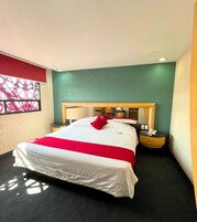 Una habitación de hotel con una cama grande, una mesita de noche con teléfono y una ventana con vistas al exterior.