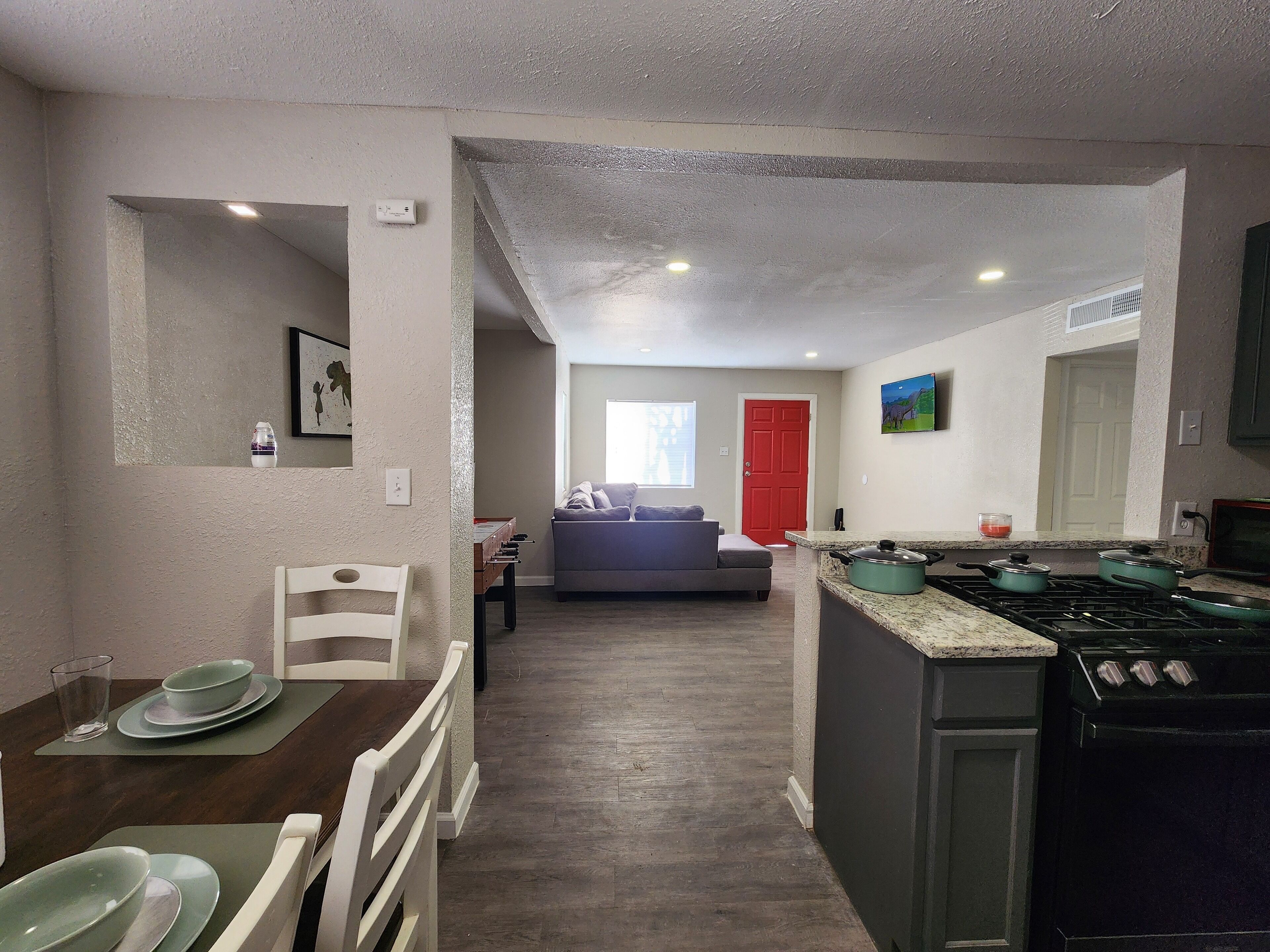 A compact kitchen with a stove, microwave, and dining area with chairs and a table.