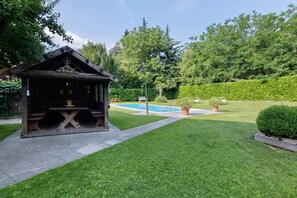 Un belvédère en bois avec une piscine en arrière-plan.