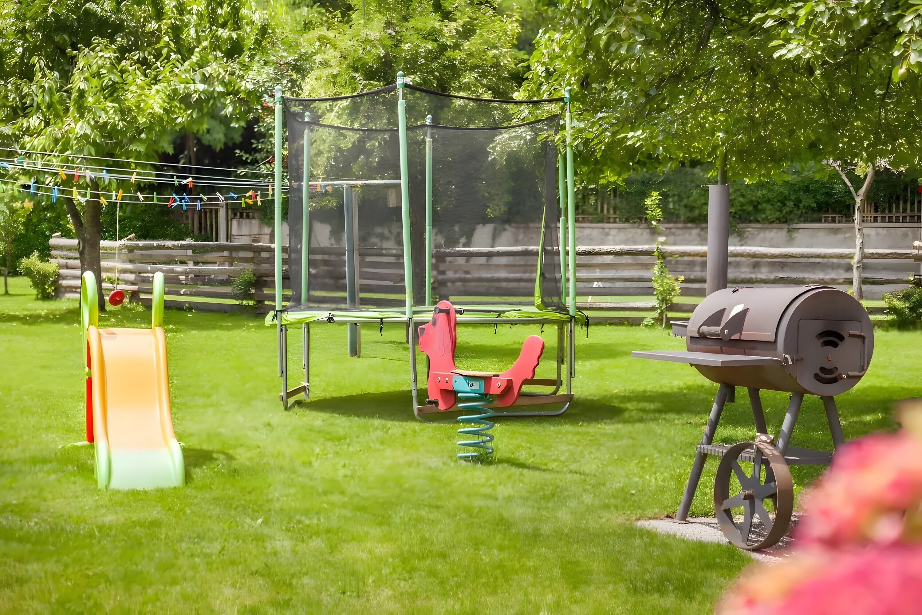 Ein Spielplatz mit Rutsche, Schaukeln und einem Grill.