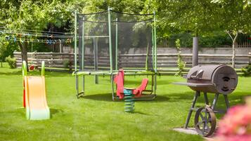 Ein Spielplatz mit Rutsche, Schaukeln und einem Grill.