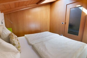 Ein Schlafzimmer mit Holzboden, einem Bett mit weißer Bettwäsche, einer grünen Wand und einer Tür mit Milchglasfenster.
