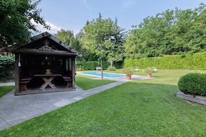 Un pabellón de madera con una piscina al fondo.