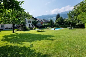 Une maison avec une piscine, entourée d’une pelouse bien entretenue et d’arbres.