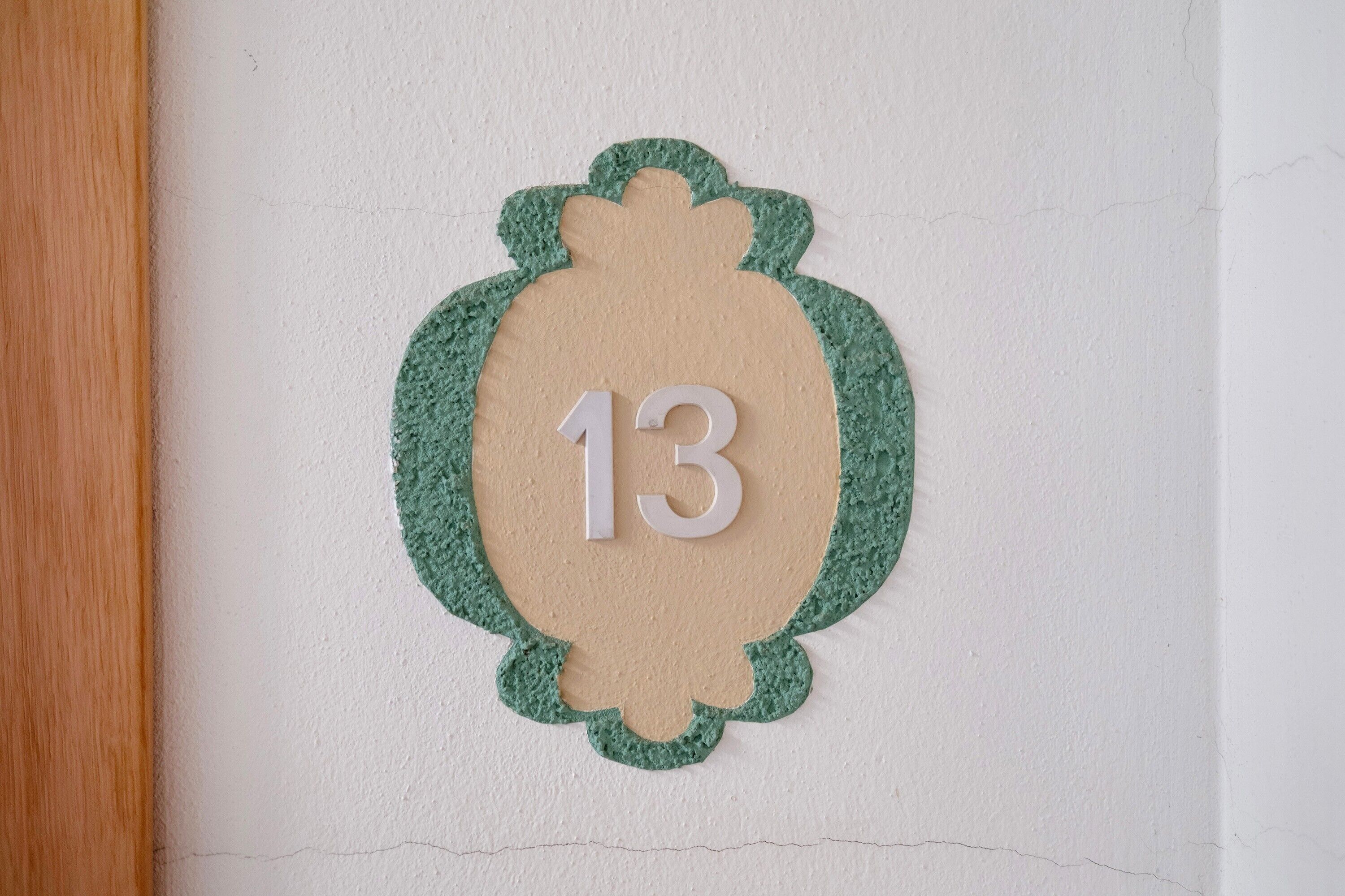 A wall-mounted number plate with the number 13.