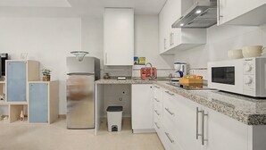 Cozinha com armários brancos, geladeira de aço inoxidável, micro-ondas e pia.