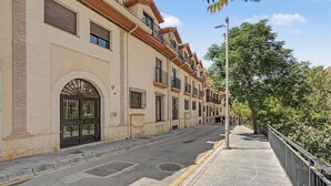 Uma rua com uma fileira de edifícios, calçada e cerca de metal.
