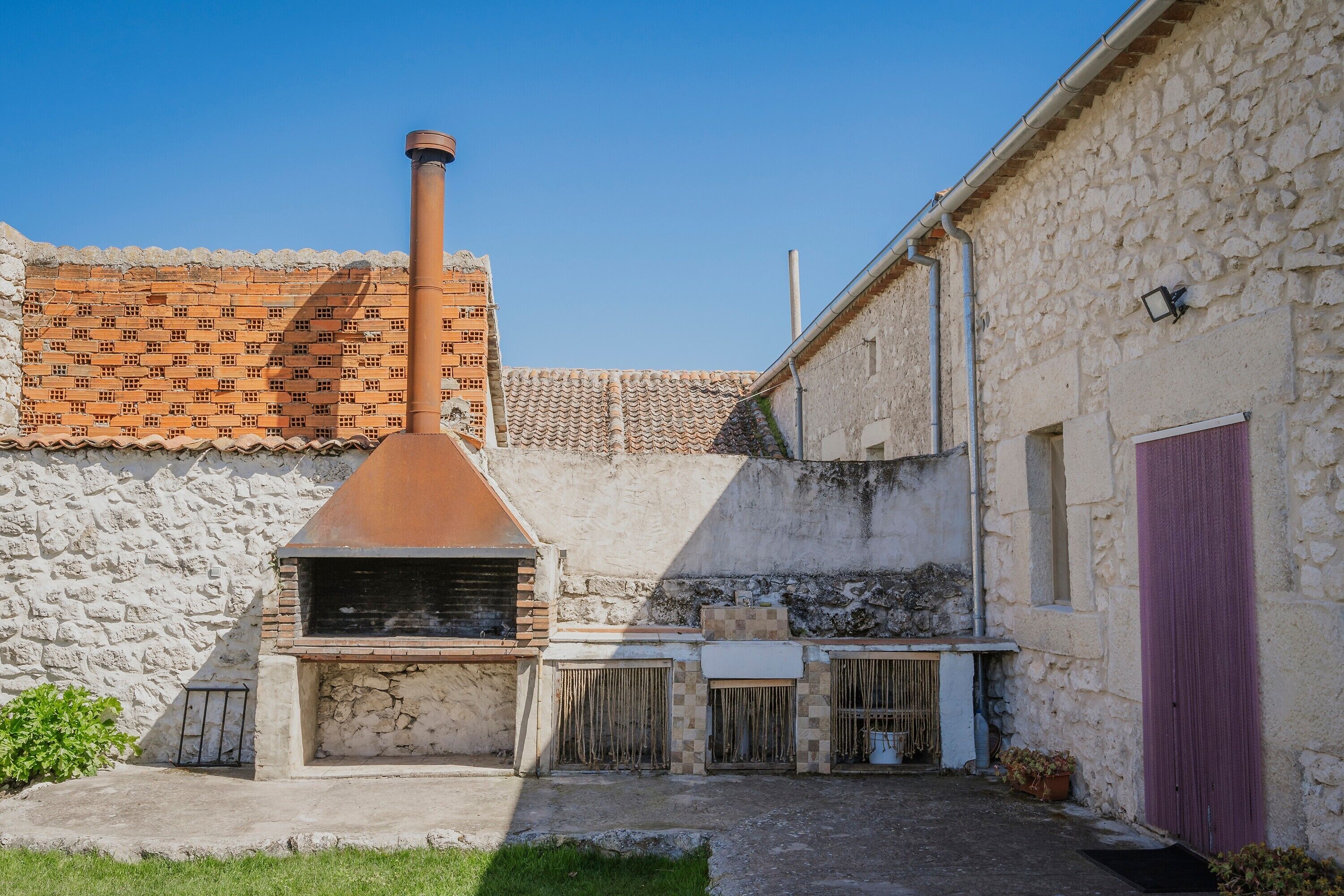 A stone building with a chimney, a tiled roof, and a door.