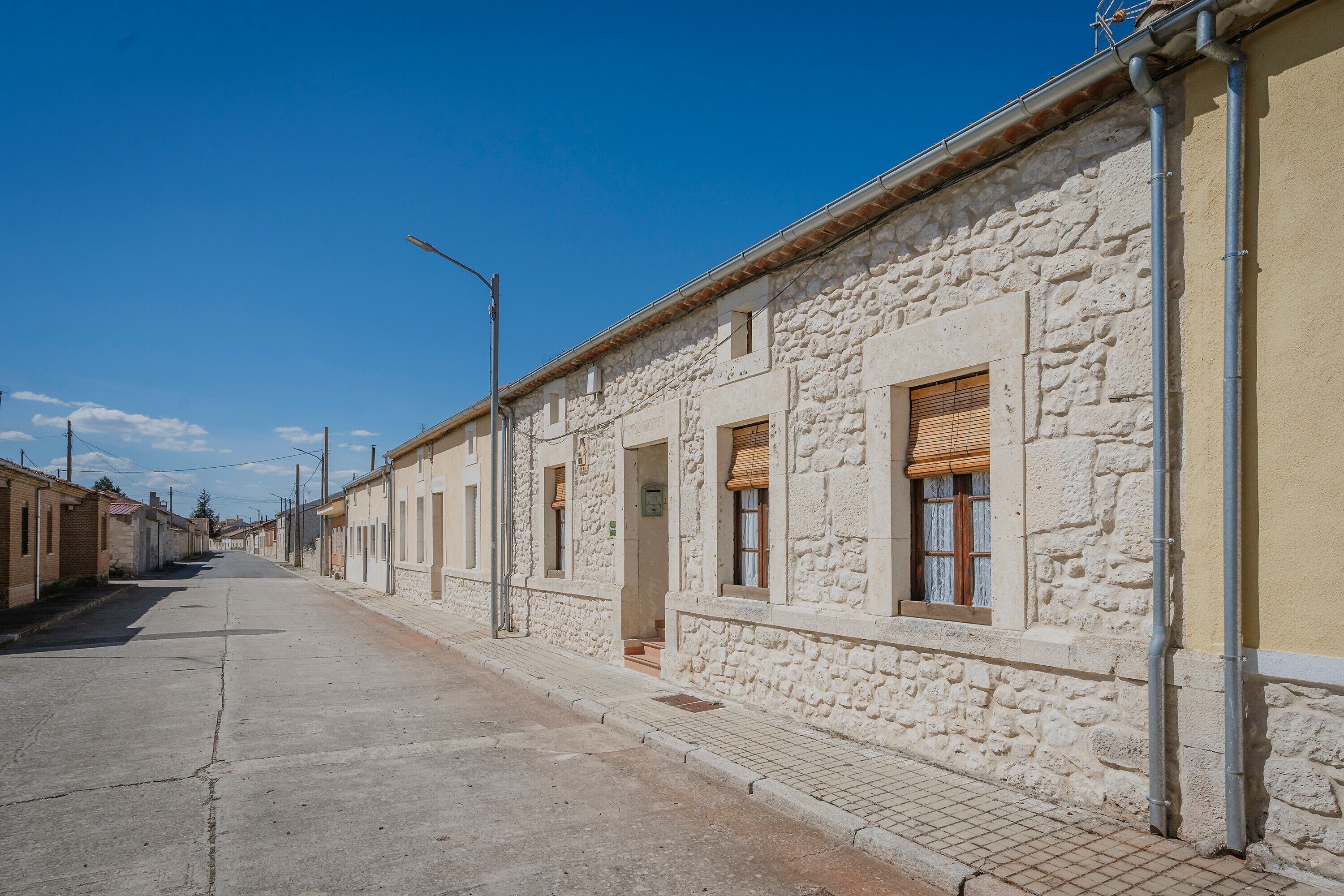 Un carrer amb edificis de pedra, cel serè i vorada.