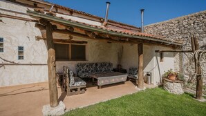 Un espace extérieur aménagé dans un style rustique, avec un mur en pierre, une pergola en bois et une cheminée en pierre.