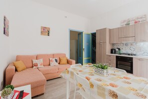 Un salon confortable avec un canapé, une table à manger et un coin cuisine équipé de placards et d’une cuisinière.