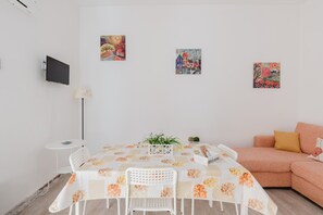 Une pièce comprenant une table à manger, des chaises, un canapé et des œuvres d’art murales.