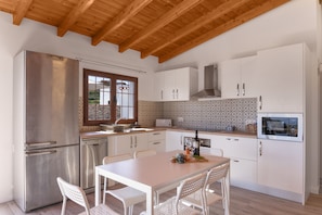 A modern kitchen with white cabinetry, stainless steel appliances, and a wooden ceiling. - Vacation Home 'Los Barranquillos' with Sea View, Private Pool, and Wi-Fi (Las Palmas)