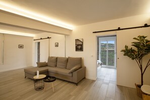 Ein modernes Wohnzimmer mit einem Ecksofa, einem kleinen runden Tisch und einer großen Kübelpflanze.