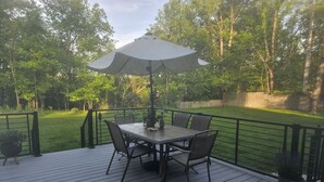 A deck with a table and chairs, surrounded by a wooden deck and a metal railing. - Rustic Modern Cabin w Hot Tub 1 5 hrs From NYC (Montgomery)