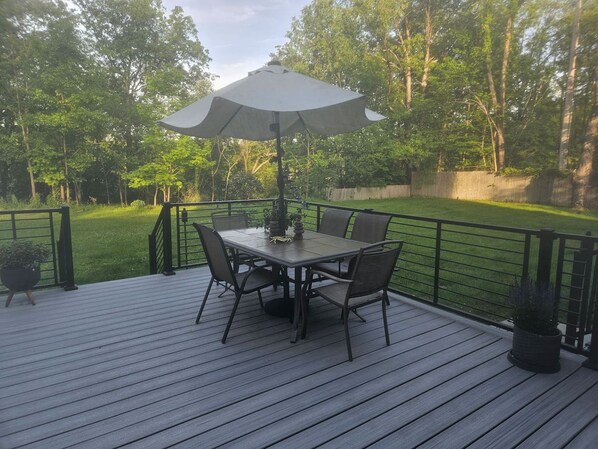 En træterrasse med et bord og stole, omgivet af både en træterrasse og et gelænder af metal.