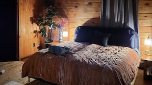 A wooden-paneled bedroom with a bed, a ceiling fan, and a nightstand with a lamp. - Rustic Modern Cabin w Hot Tub 1 5 hrs From NYC (Montgomery)