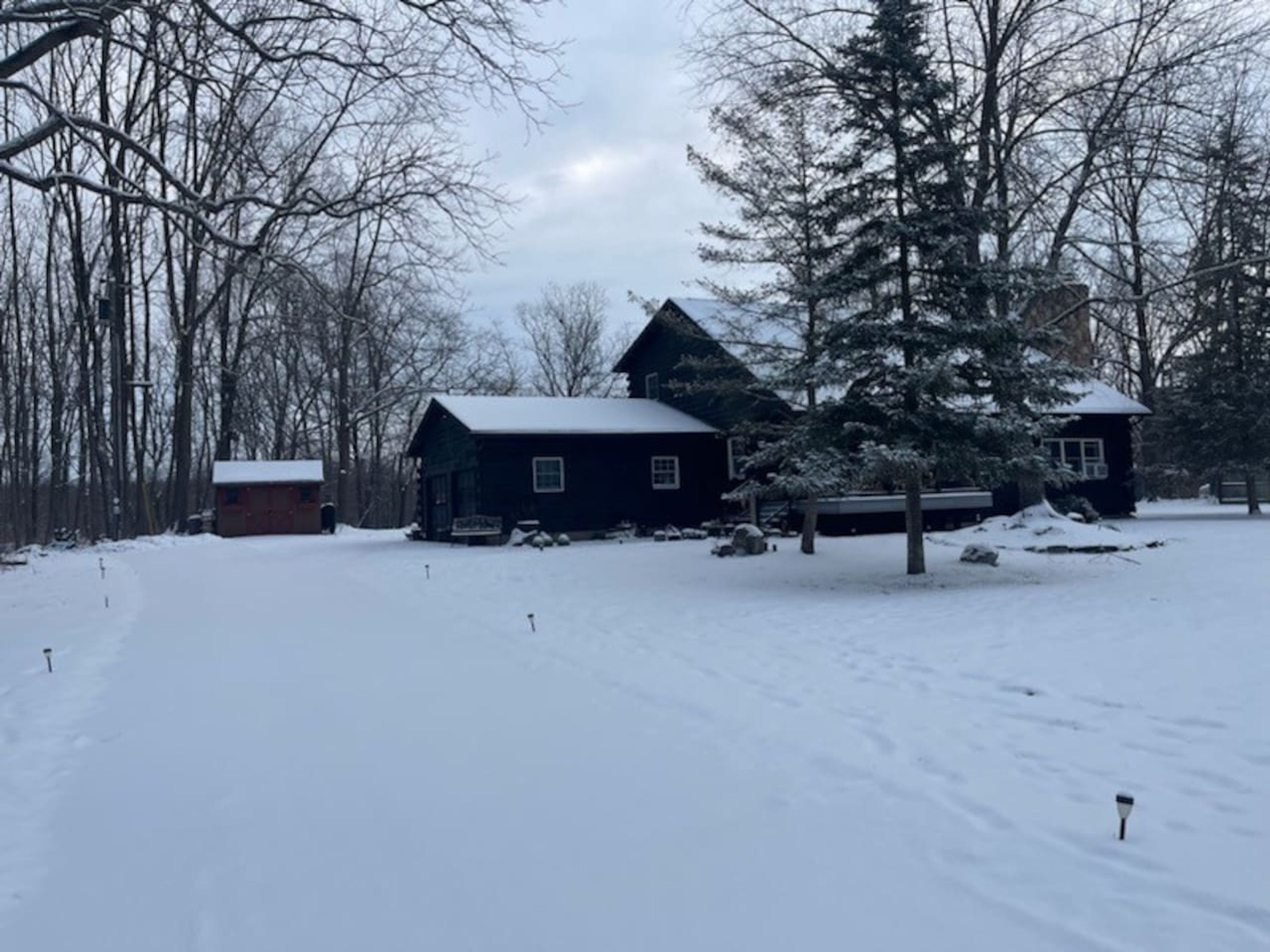 A cabin with a snow-covered roof, surrounded by trees and a snowy landscape.