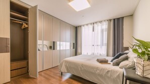 A bedroom with a bed, a wardrobe, and a bedside table with a plant. - Sejong Party House  (Busan)