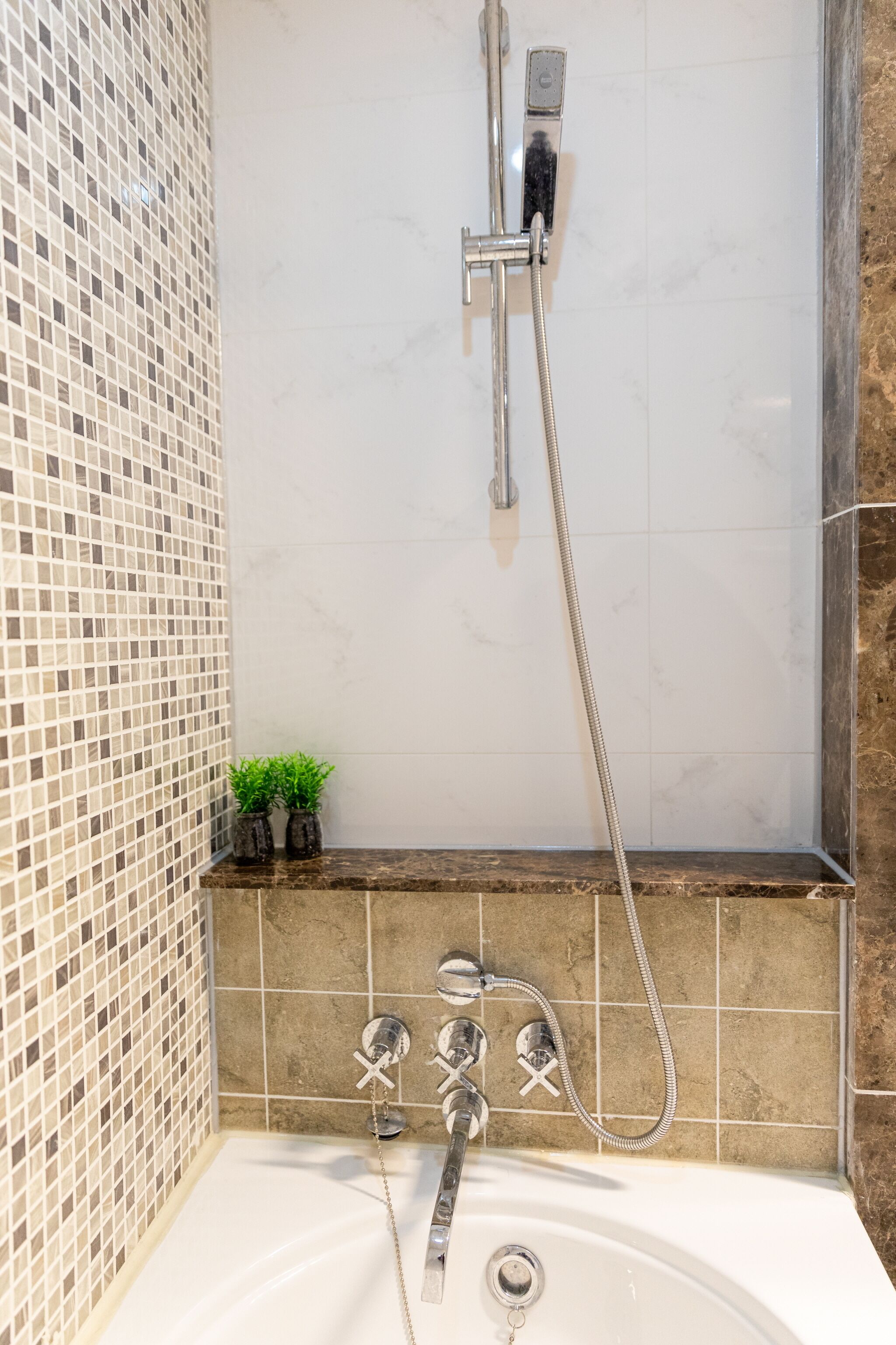 A bathroom with a shower, a bathtub, and a tiled wall.