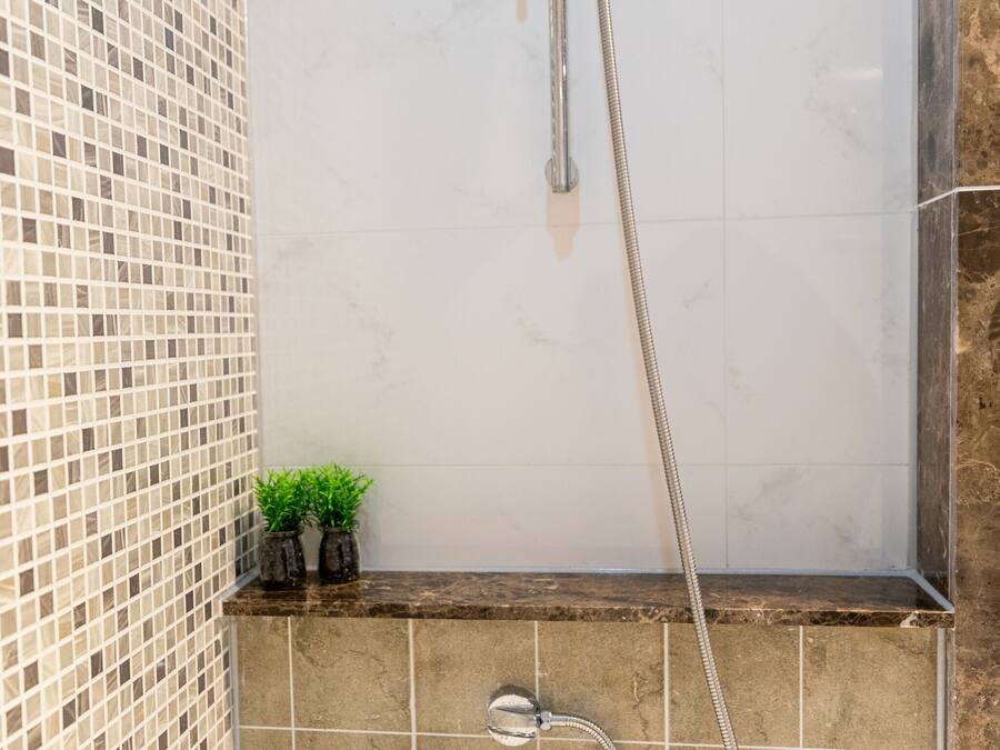A bathroom with a shower, a bathtub, and a tiled wall.