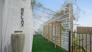 A white wall with the word 'RELAX' and a large vase. There is a hammock and wooden lattice structures. - Los Adejo Vacation Home with Shared Heated Pool, Terrace, and Wi-Fi (Moya)
