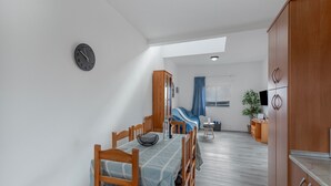 A dining area with a table and chairs, a clock on the wall, a wardrobe, and a window with curtains. - Los Adejo Vacation Home with Shared Heated Pool, Terrace, and Wi-Fi (Moya)