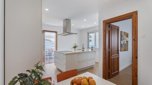 Una cocina moderna con una isla central, una mesa de comedor con un bol de naranjas y una planta en maceta.
