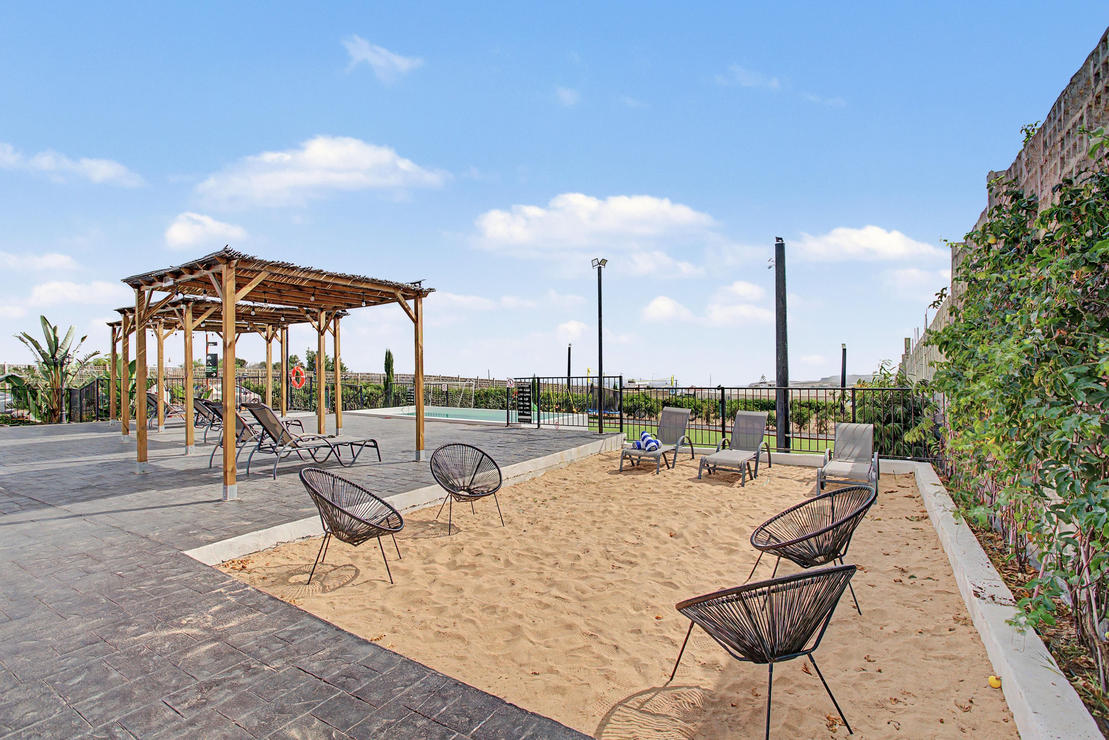 Een overdekt terras met loungesessels en een pergola.