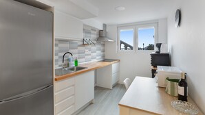 A modern kitchen with a stainless steel refrigerator, a wooden countertop, a sink, and a window with a city view. - ‘Hacienda Los Adejo’ with Heated Private Pool, Mountain Views, and Wi-Fi (Moya)