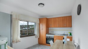 Una cucina funzionale con mobili in legno, forno integrato, tavolo da pranzo e finestra con tende.