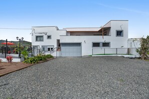 Een modern huis met twee verdiepingen, een witte gevel, een garage en een oprit met grind.