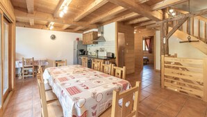 A wooden interior with a dining table, chairs, a kitchen area, and a staircase. - Chalet 'Les Laouchets -  8 Pers' with Mountain View, Balcony and Wi-Fi (Sixt-Fer-à-Cheval)