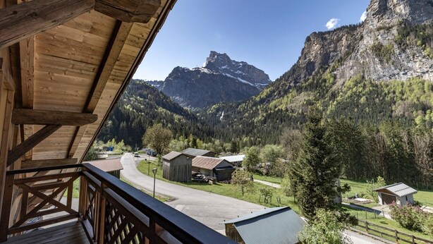 A wooden structure with a view of a mountain landscape, including a prominent peak and a valley with buildings. - Chalet 'Les Laouchets -  8 Pers' with Mountain View, Balcony and Wi-Fi (Sixt-Fer-à-Cheval)